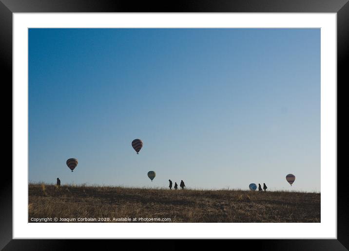Goreme, Turkey - April 4, 2012: Hot air balloons for tourists flying over rock formations at sunrise in the valley of Cappadocia. Framed Mounted Print by Joaquin Corbalan