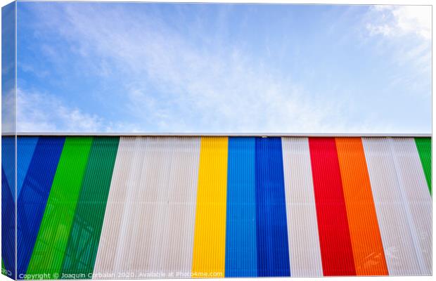 Facade with colored lines, against the blue sky in the background. Canvas Print by Joaquin Corbalan