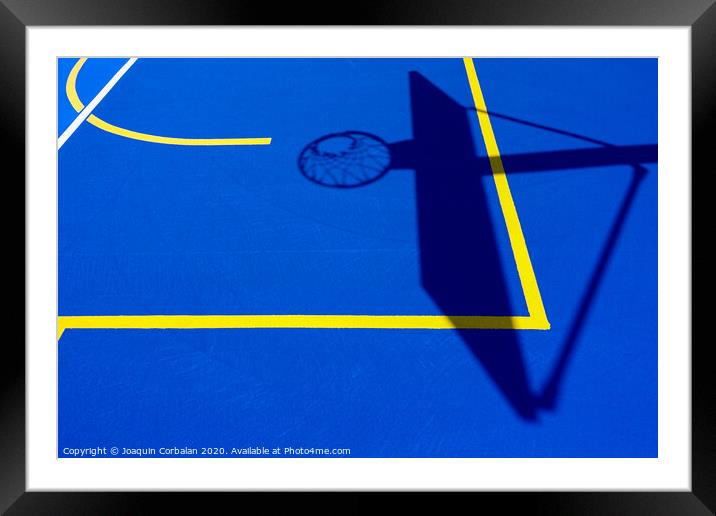 Shadow of a basketball basket on the floor of the court, painted blue and background with lines. Framed Mounted Print by Joaquin Corbalan