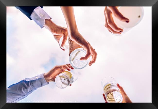 Group of friends toasting with a few glasses of alcohol with the sky in the background, seen from below. Framed Print by Joaquin Corbalan