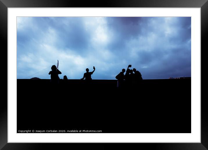 Silhouette of a group of unrecognizable people using their smartphones, socially isolated. Framed Mounted Print by Joaquin Corbalan