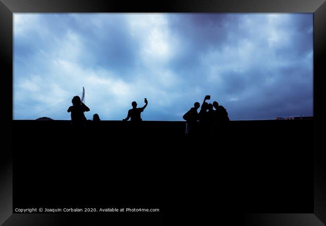 Silhouette of a group of unrecognizable people using their smartphones, socially isolated. Framed Print by Joaquin Corbalan