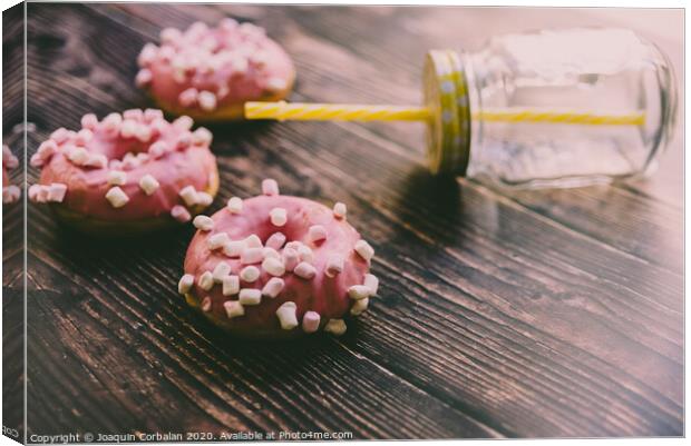 Pair of buns frosted with pink sugar and unhealthy marshsmallows next to a glass jar. Canvas Print by Joaquin Corbalan