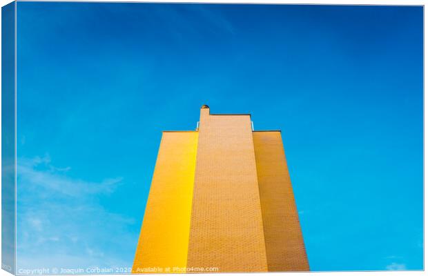High brick building, warm and yellow at sunset, with the background of an intense blue sky and copy space, minimalist architecture. Canvas Print by Joaquin Corbalan