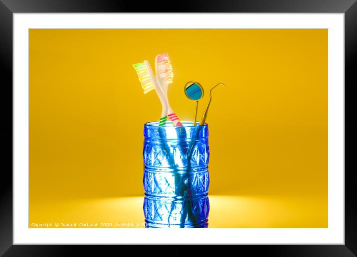New plastic toothbrushes inside a glass, isolated on bright orange background, with copy space. Framed Mounted Print by Joaquin Corbalan