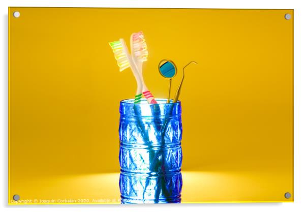 New plastic toothbrushes inside a glass, isolated on bright orange background, with copy space. Acrylic by Joaquin Corbalan