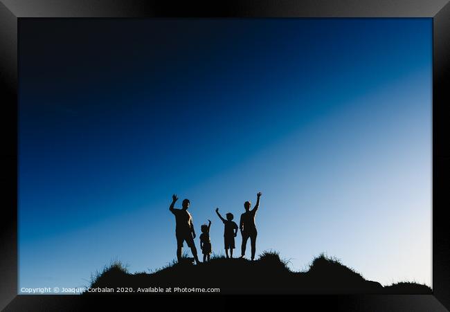 Silhouette of a happy family on top of a hill waving at sunset. Framed Print by Joaquin Corbalan
