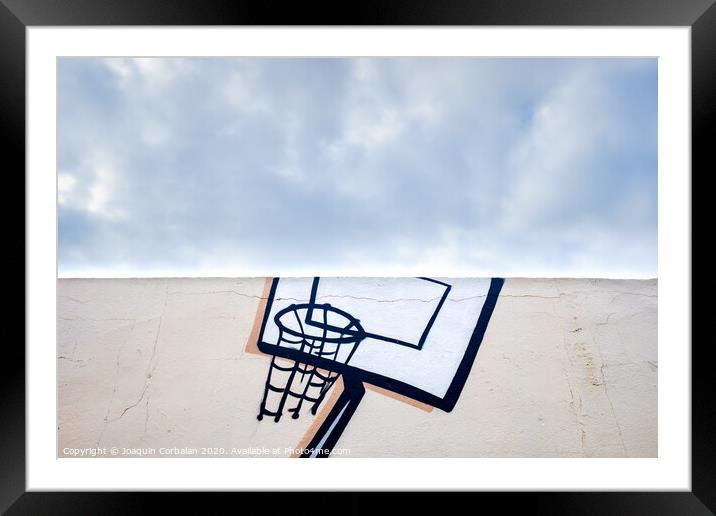 Outdoor basketball court decorated with street graffiti, half with blue sky and clouds in the background. Framed Mounted Print by Joaquin Corbalan