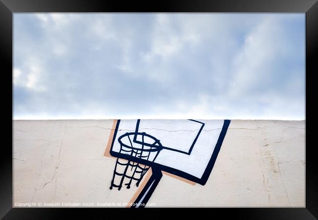 Outdoor basketball court decorated with street graffiti, half with blue sky and clouds in the background. Framed Print by Joaquin Corbalan