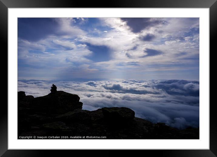Pile of stones on a backlit path to guide hikers to the mountain peak, on a day of clouds. Framed Mounted Print by Joaquin Corbalan