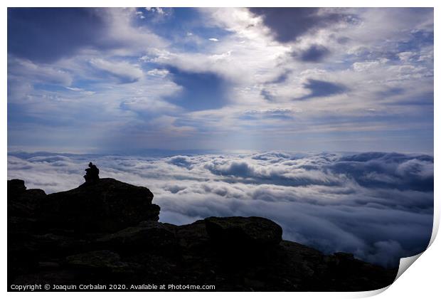 Pile of stones on a backlit path to guide hikers to the mountain peak, on a day of clouds. Print by Joaquin Corbalan