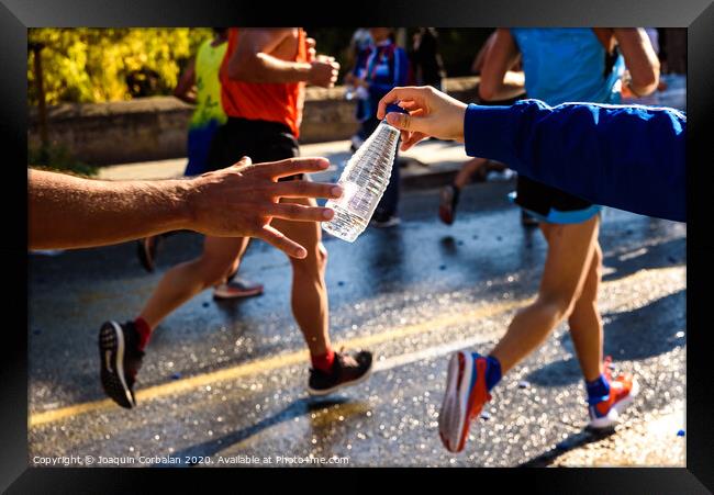 Runner collects a bottle of water to hydrate during a workout. Framed Print by Joaquin Corbalan