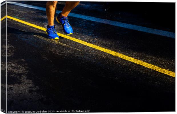 A lonely runner trains on wet asphalt at sunset, copy space. Canvas Print by Joaquin Corbalan