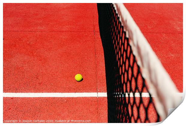 A tennis ball on the textured floor of a red court near the net after losing a match point. Print by Joaquin Corbalan
