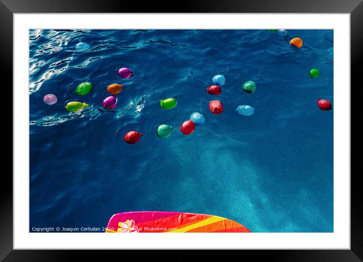 Group of many colorful plastic water balloons floating in the water of a pool to entertain their children on summer vacations. Framed Mounted Print by Joaquin Corbalan