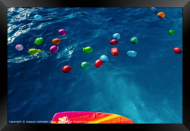 Group of many colorful plastic water balloons floating in the water of a pool to entertain their children on summer vacations. Framed Print by Joaquin Corbalan