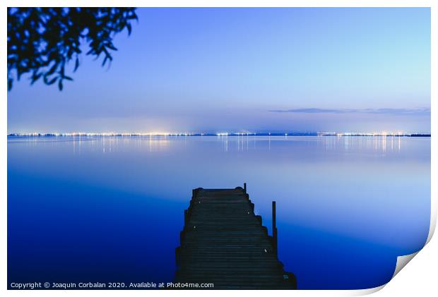 Pier on a lake at sunset with calm water and reflections of relaxing lights. Print by Joaquin Corbalan
