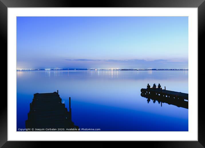 People resting relaxed on a pier on a lake at sunset with calm water Framed Mounted Print by Joaquin Corbalan