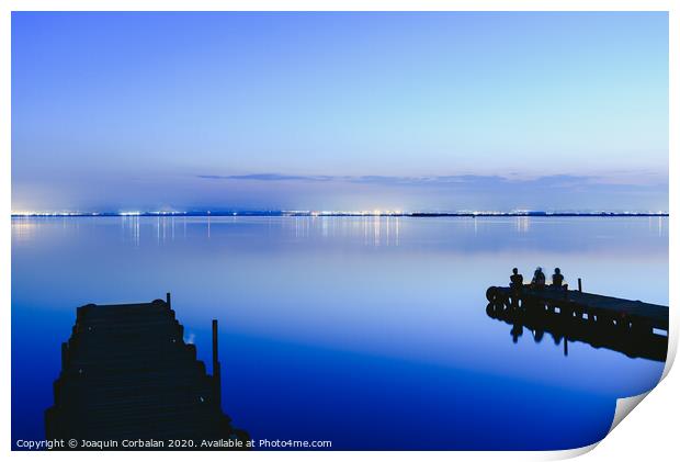 People resting relaxed on a pier on a lake at sunset with calm water Print by Joaquin Corbalan