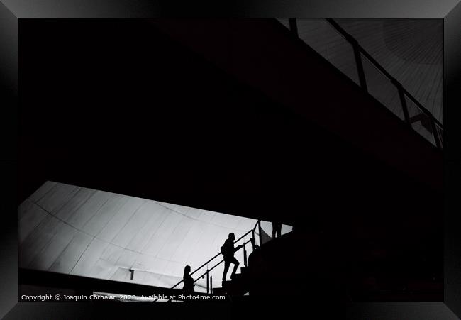 Silhouettes of people inside a building crossing stairs and walkways. Framed Print by Joaquin Corbalan