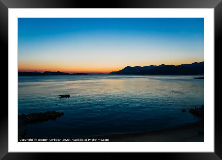 Sunset in a bay with mountains in the background and a small boat anchored. Framed Mounted Print by Joaquin Corbalan