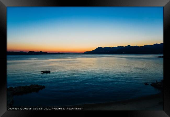 Sunset in a bay with mountains in the background and a small boat anchored. Framed Print by Joaquin Corbalan