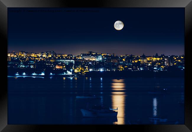 Night view of Cascais, Portugal with full moon reflecting on water and fishing boats Framed Print by Alexandre Rotenberg