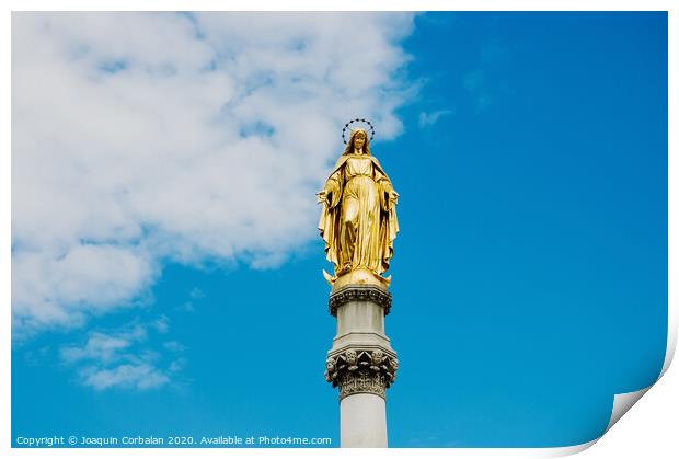 Golden religious statue, illuminated by the sun, of the Virgin Mary on top of a pedestal, with a background of blue sky and clouds. Print by Joaquin Corbalan