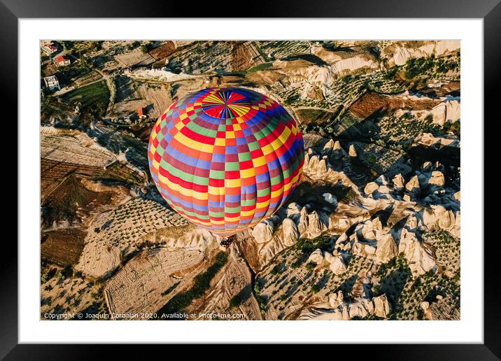 Travelers and tourists flying over mountains at sunset in a colorful aerostat balloon in Goreme, the Turkish cappadocia. Framed Mounted Print by Joaquin Corbalan