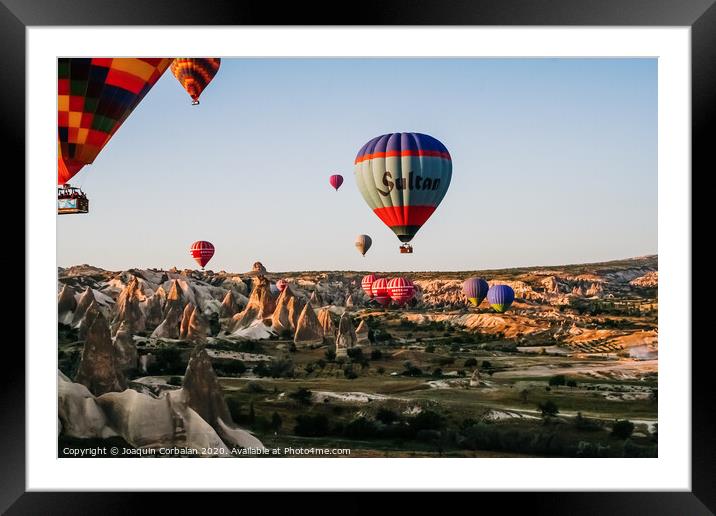 Travelers and tourists flying over mountains at sunset in a colorful aerostat balloon in Goreme, the Turkish cappadocia. Framed Mounted Print by Joaquin Corbalan