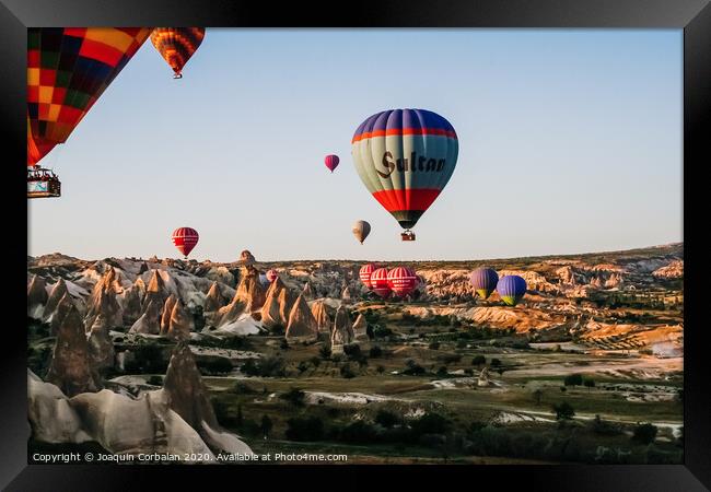 Travelers and tourists flying over mountains at sunset in a colorful aerostat balloon in Goreme, the Turkish cappadocia. Framed Print by Joaquin Corbalan