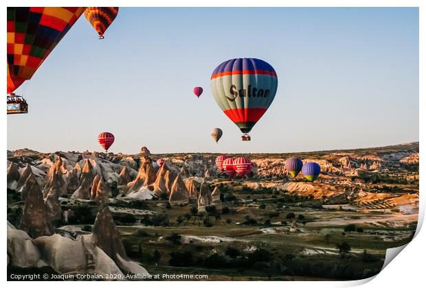 Travelers and tourists flying over mountains at sunset in a colorful aerostat balloon in Goreme, the Turkish cappadocia. Print by Joaquin Corbalan