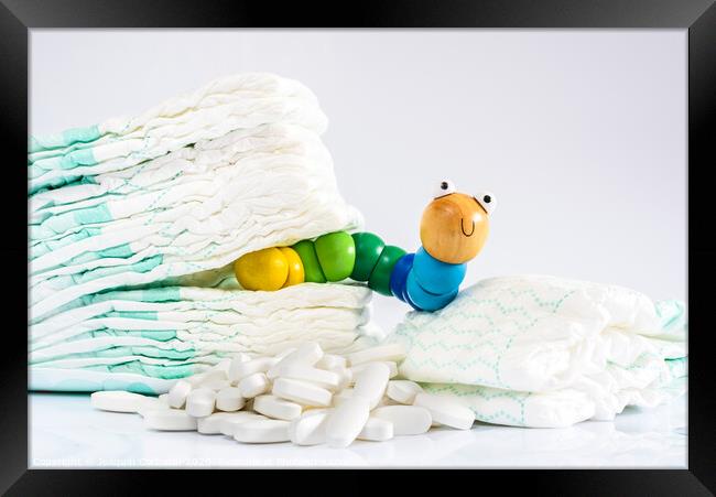 Enterobiasis is a infections of worms, Enterobius vermicularis or pinworms, which affects children and babies. A toy worm with some diapers and pills. Framed Print by Joaquin Corbalan