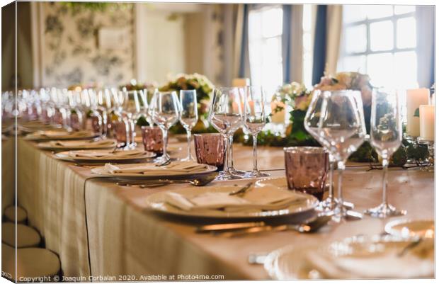 Elongated table with all the cutlery elegantly arranged and beautiful centerpieces ideal for decorating a wedding. Canvas Print by Joaquin Corbalan