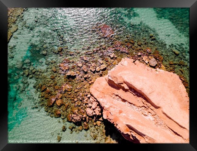 Aerial view of a natural rock jetty on the Mediterranean coast with transparent turquoise waters. Framed Print by Joaquin Corbalan