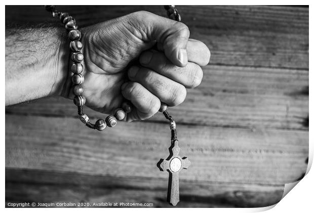 Hand of a religious person holds a Christian rosary during his prayers, unfocused background of woods in black and white. Print by Joaquin Corbalan