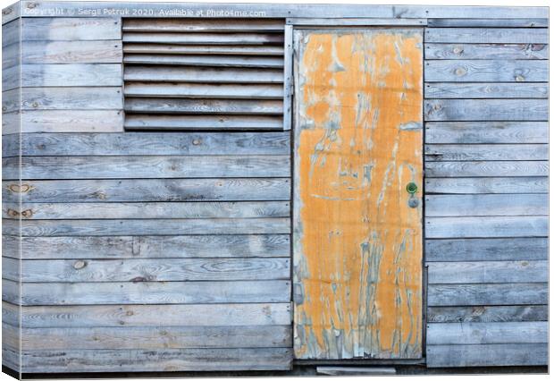 Wooden old weather-beaten barn with a yellow old door Canvas Print by Sergii Petruk
