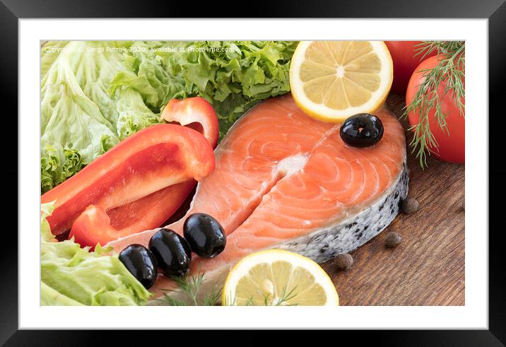 Raw salmon steak on a wooden board surrounded by vegetables, black olives and spices. Framed Mounted Print by Sergii Petruk