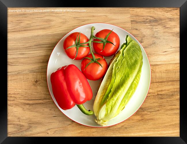 Bulgarian pepper, tomato and romaine lettuce lie close-up on a white round porcelain plate against the background of a wooden table Framed Print by Sergii Petruk