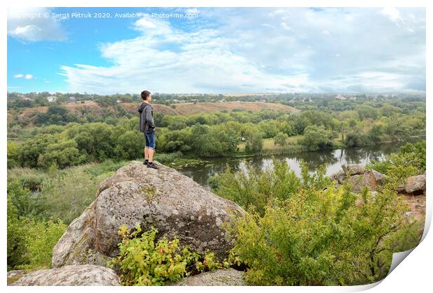 The teenager stands on top of a large stone boulder on the bank of the Southern Bug River and looks at the river below Print by Sergii Petruk