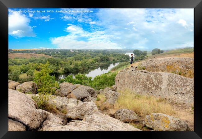 The teenager stands on top of a large stone boulder on the bank of the Southern Bug River and looks at the river below Framed Print by Sergii Petruk