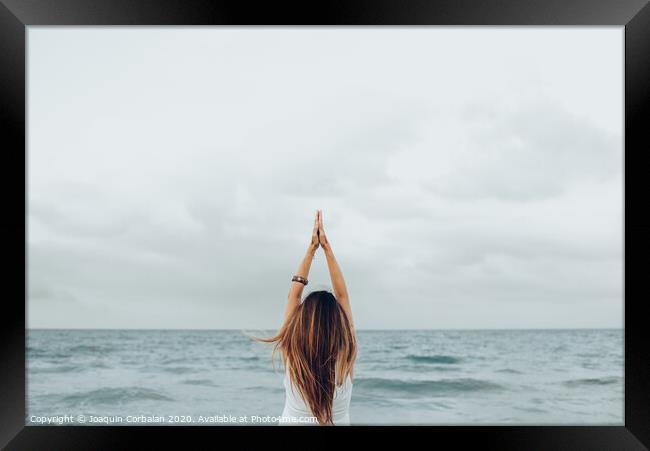 A woman relaxes in front of the sea with her hands up, unfocused background. Framed Print by Joaquin Corbalan