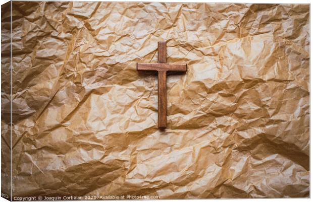 Simple wooden religious cross on brown paper background. Canvas Print by Joaquin Corbalan