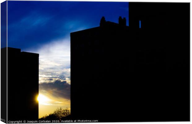 Sunset silhouette in a city with the warm sun behind buildings. Canvas Print by Joaquin Corbalan