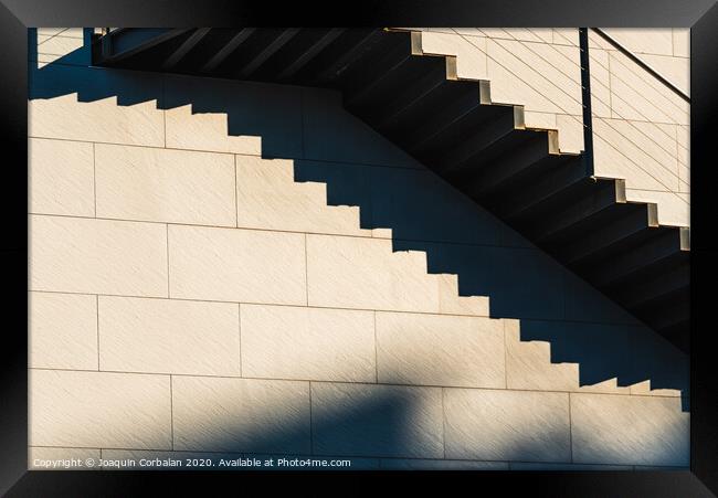 Minimalist wall with shadows from the upper steps of a modern stone staircase. Framed Print by Joaquin Corbalan