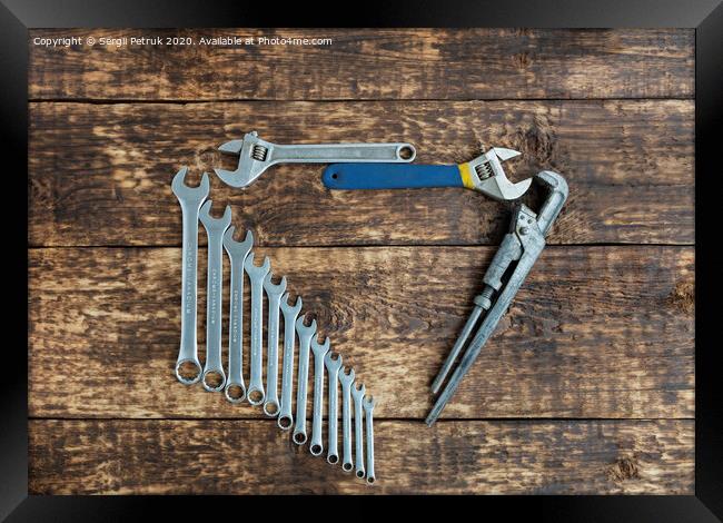 Set of combination wrenches and old adjustable wrenches on an old wooden background Framed Print by Sergii Petruk