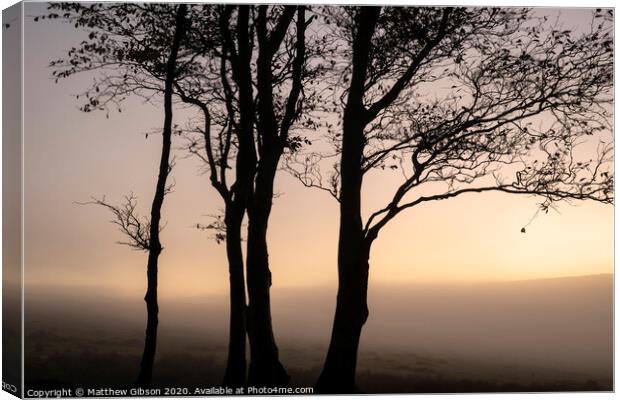 Beautiful foggy sunrise landscape over the tors in Dartmoor revealing peaks through the mist Canvas Print by Matthew Gibson