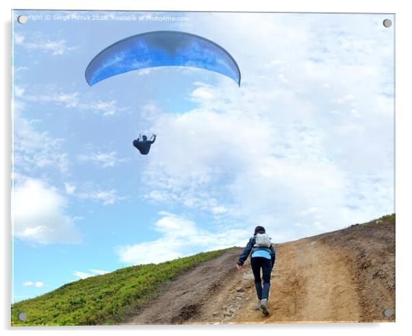 A young woman climbs up a mountain to meet a paraglider hovering in the air Acrylic by Sergii Petruk