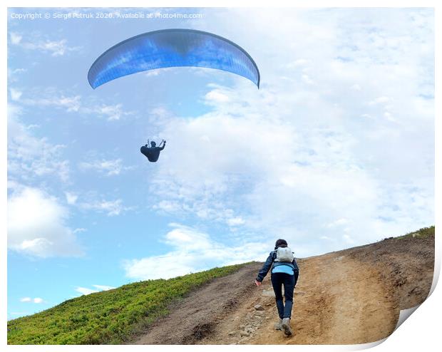 A young woman climbs up a mountain to meet a paraglider hovering in the air Print by Sergii Petruk