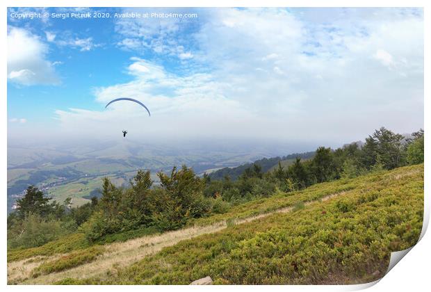 A flying paraglider against the blue sky, in the morning fog of the Carpathian Mountains Print by Sergii Petruk